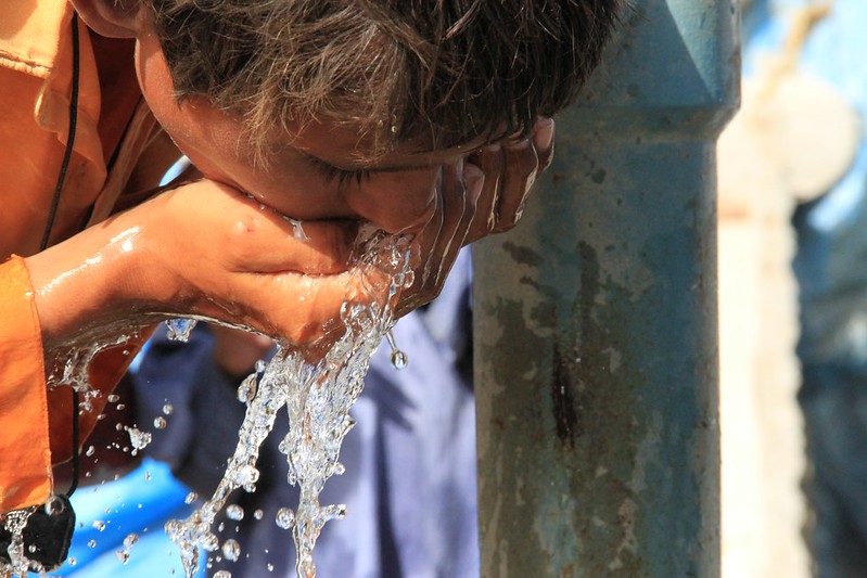 Person drinking from an open air tap