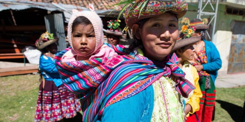 Mother with child on her back, both wearing colourful clothes