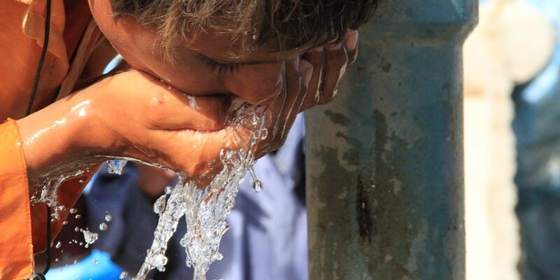 Person drinking from an open air tap